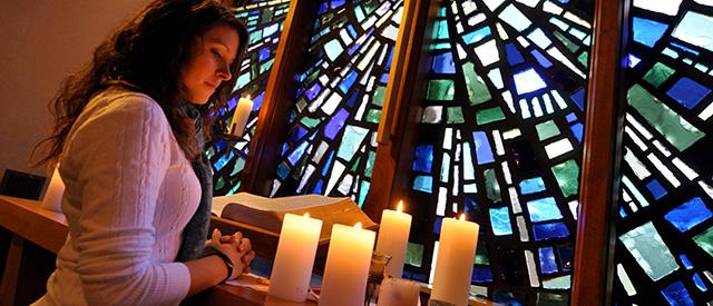 student looking at candles in chapel